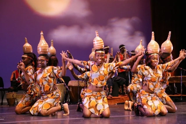 Dancers performing on stage with pots balanced on their heads